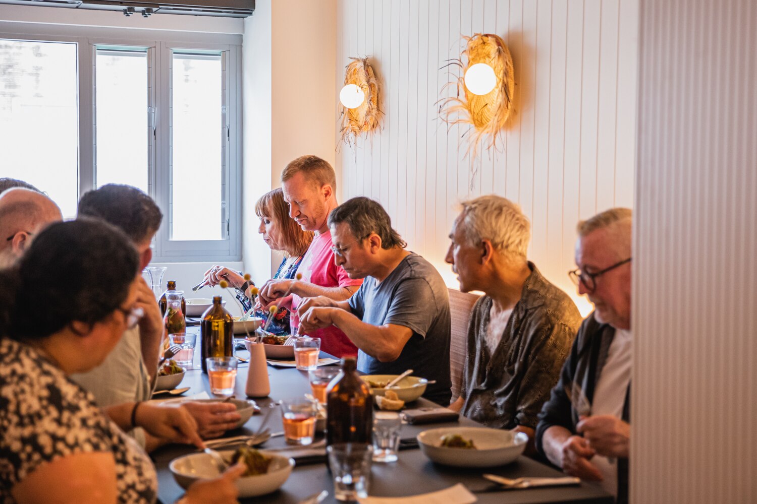 几个男人和女人坐在白墙餐厅的一张桌子旁吃饭